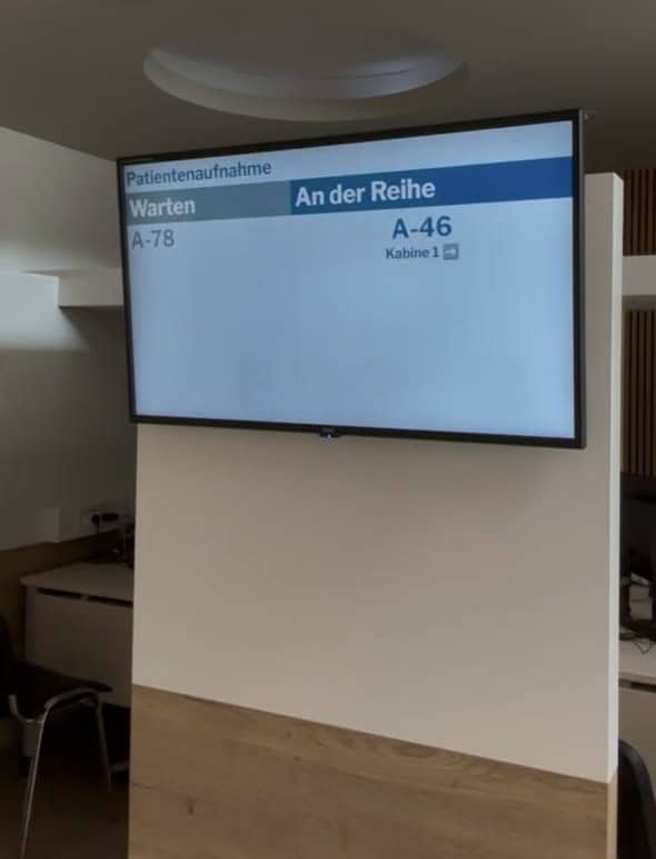 Quickticket Patientenaufrufsystem auf einem Praxismonitor mit Warten- und Aufrufanzeige